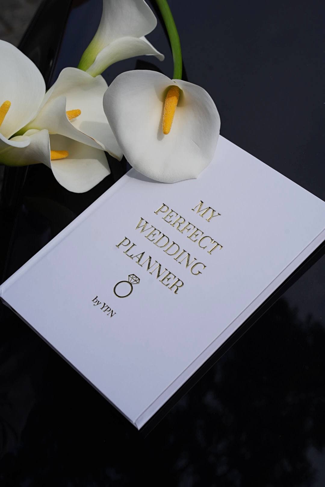 Білий весільний планер My Perfect Wedding Planner by YPN поруч із каллами